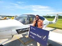 Isaiah Hand holds sign as he stands at the plane in which he earned his license. Credit: Tuskegee University