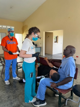 Dr. Roger Phanord of Phanord & Associates, right, assists dental students as they provide care to a patient during a missionary trip to Las Matas de Farfan, Dominican Republic.